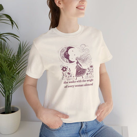 Empowering feminist t-shirt with illustrated woman walking under the moon, floral design, and the quote "She walks with the weight of every woman silenced."
