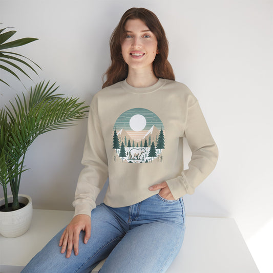 Woman wearing a beige sweatshirt with a nature graphic sitting on a white surface.