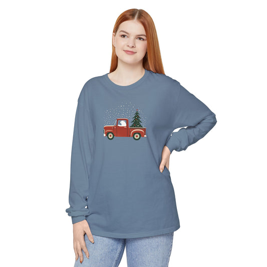 Woman wearing a blue long-sleeve shirt with a red truck and Christmas tree design on a white background