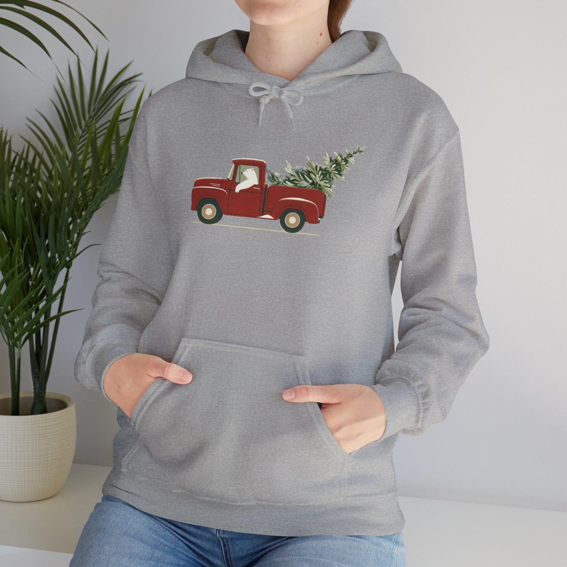 Person wearing a gray hoodie with a red truck and Christmas tree design, standing against a neutral background.