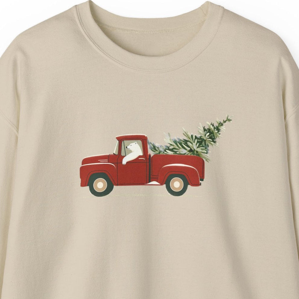 Beige sweatshirt with a polar bear driving a red truck and Christmas tree design on a white background