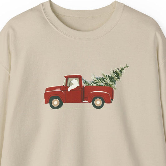 Beige sweatshirt with a polar bear driving a red truck and Christmas tree design on a white background