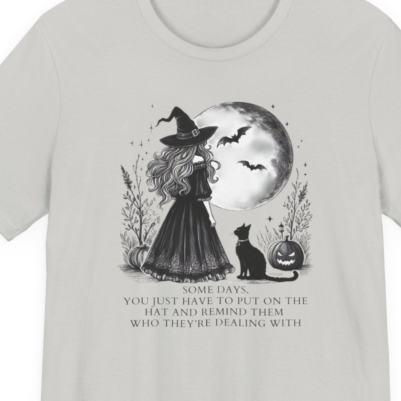 White t-shirt with text and a witch with a moon and cat graphic on a background
