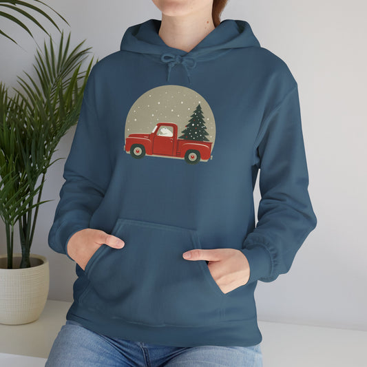 Person wearing a blue hoodie with a red truck and Christmas tree design, standing indoors.